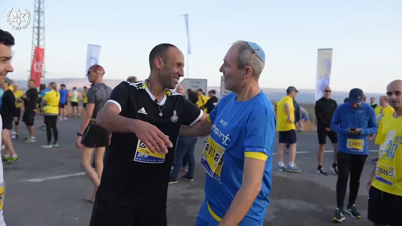 רס"מ אייל בן-סימון ורץ המרתון שהציל רוברט בלומנטל מתחבקים בסיום הריצה בחצי מרתון עמק המעיינות