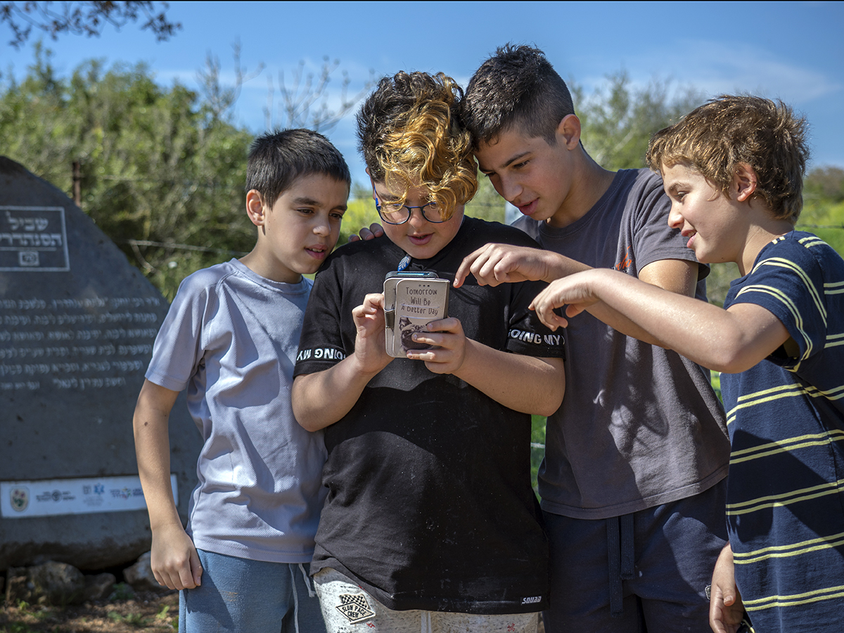תלמידים בוחנים את אפליקצית שביל הסנהדרין לצד האבן החכמה שהוצבה לאורך המסלול. צילום יניב ברמן רשות העתיקות3.