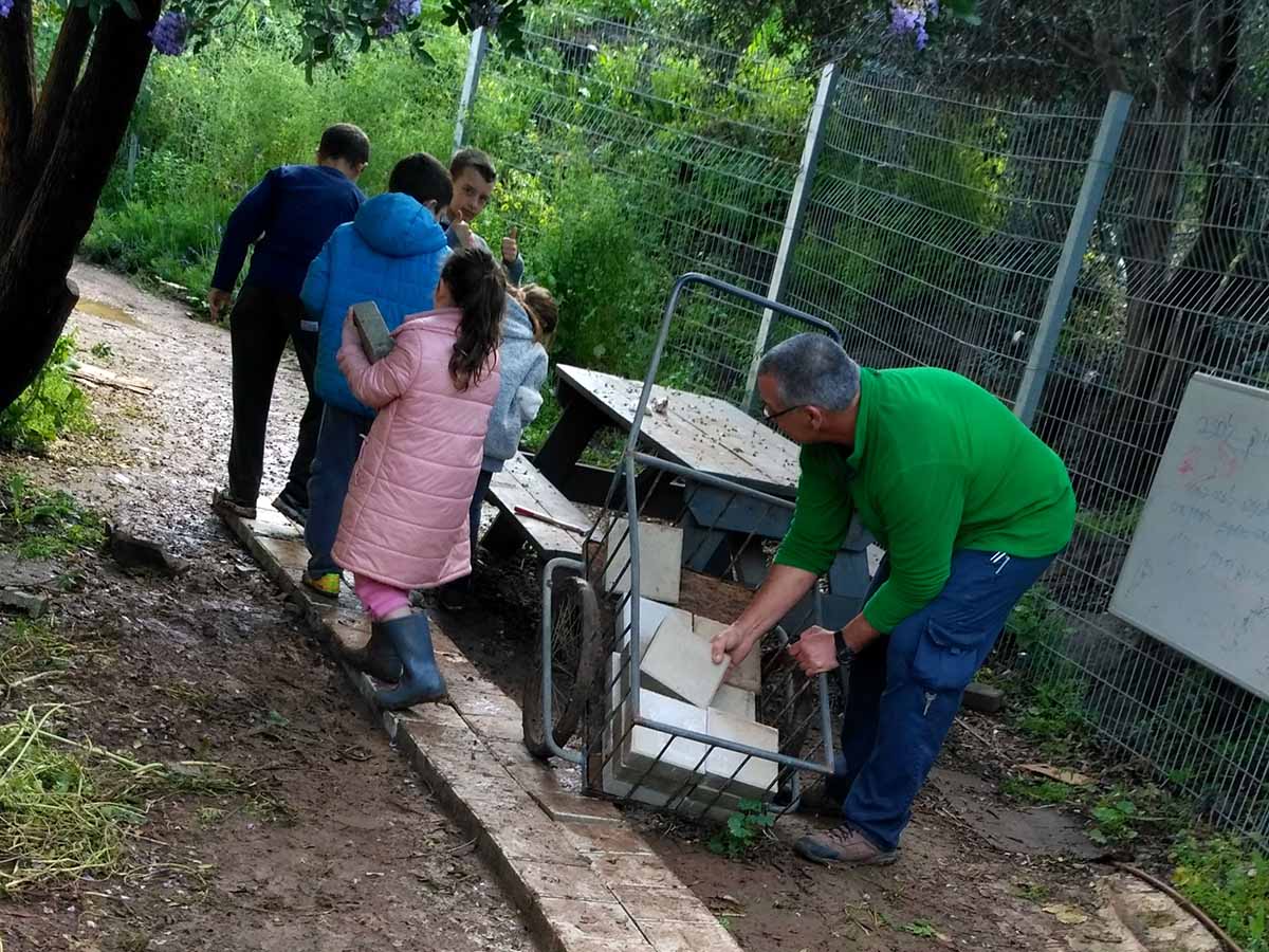 התלמידים בונים מדרכה יחד עם המנהל אורי ברזק