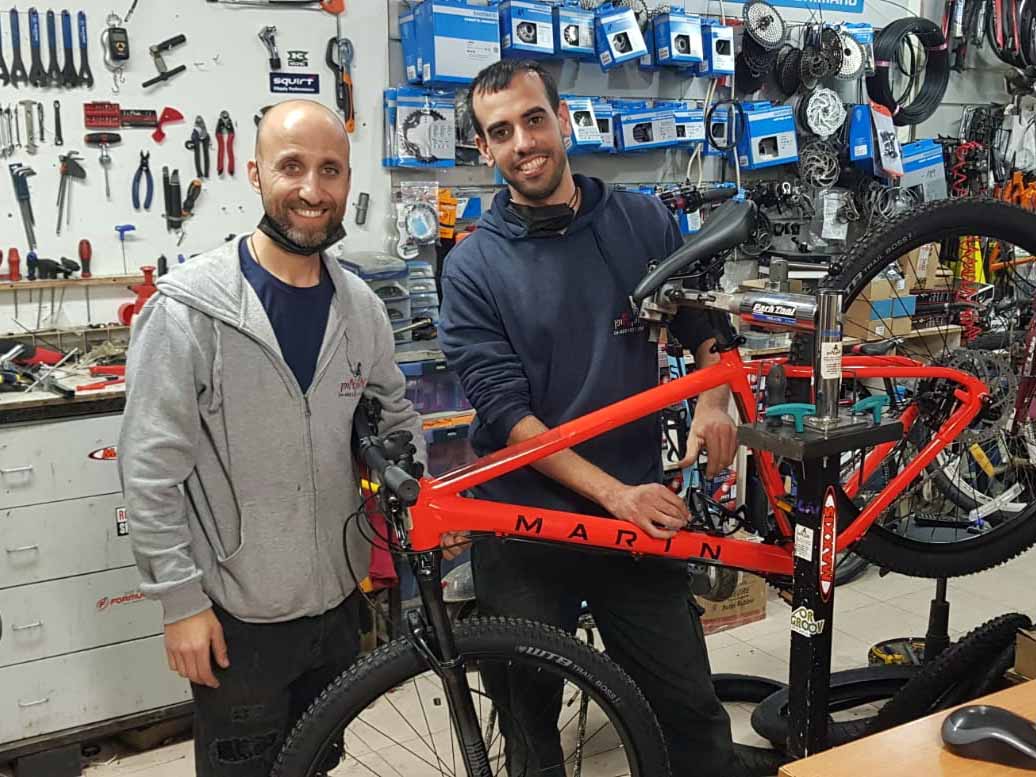 קובי קובי שושני ורן אלופי העולם מחנות האופניים מס' 1 בעפולה אופן אופן על רקע אופני ה"מרין" החדשות שנחתו בחנות.